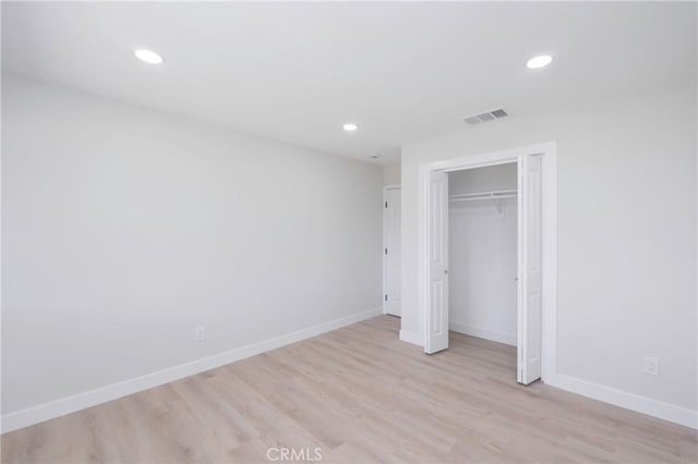 unfurnished bedroom with light hardwood / wood-style flooring and a closet