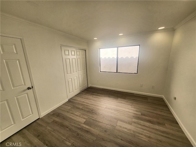 unfurnished bedroom with dark wood-type flooring, ornamental molding, and a closet