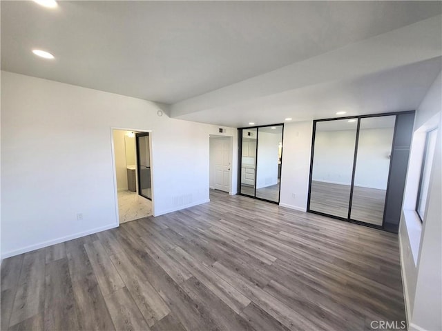 unfurnished bedroom featuring light hardwood / wood-style floors, multiple closets, and ensuite bathroom