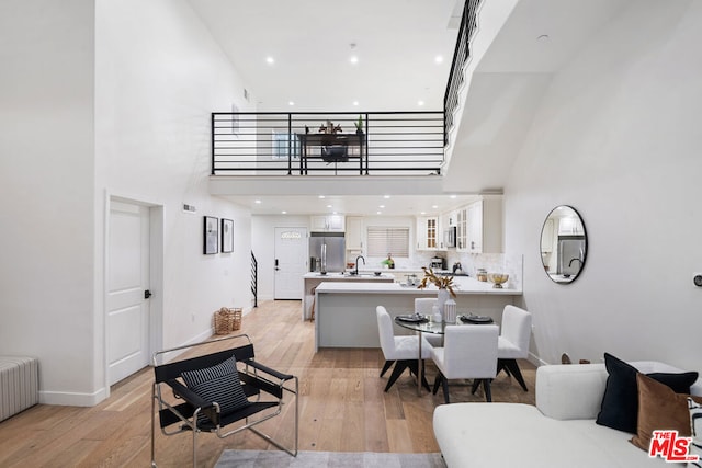 living room featuring light wood-type flooring, a towering ceiling, and radiator