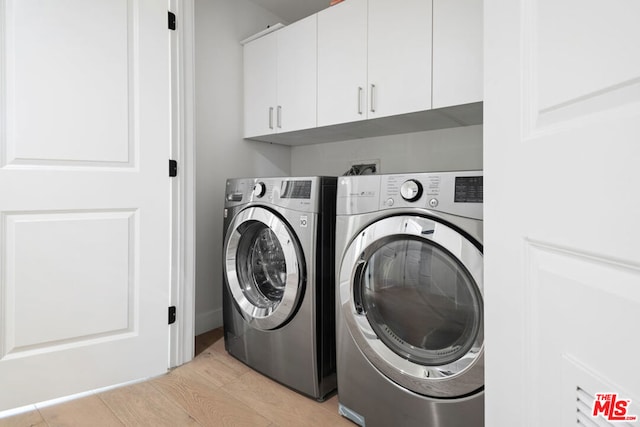 laundry area with washing machine and dryer, light hardwood / wood-style flooring, and cabinets