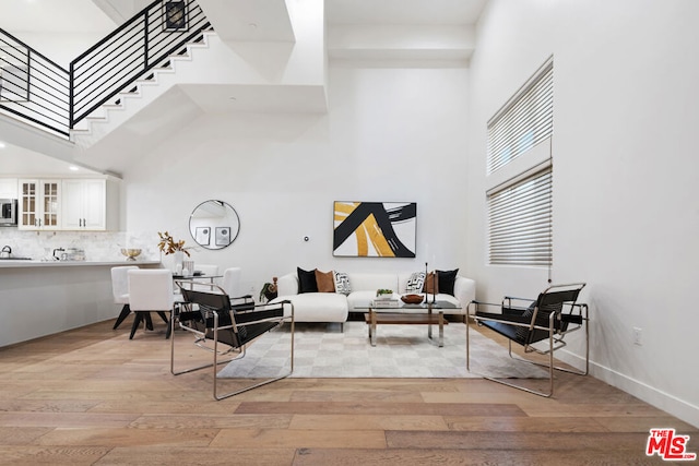 living room with light hardwood / wood-style flooring and a towering ceiling