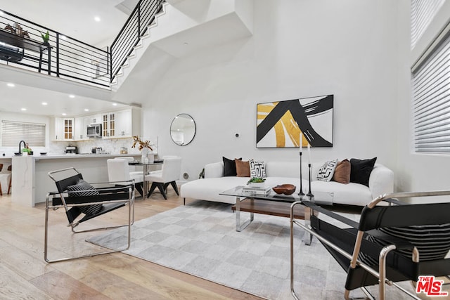 living room with a towering ceiling and light hardwood / wood-style flooring