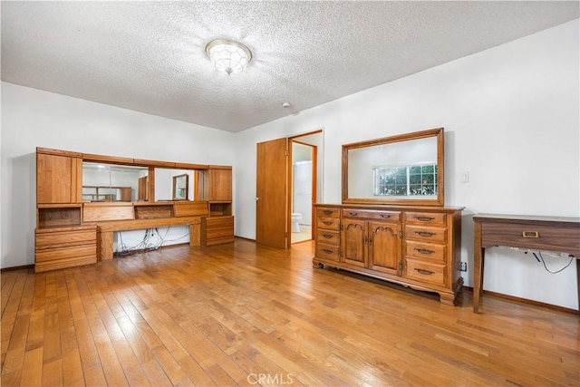 interior space featuring a textured ceiling, built in desk, and light hardwood / wood-style flooring