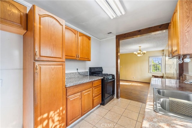 kitchen featuring an inviting chandelier, sink, black gas range oven, and light hardwood / wood-style flooring