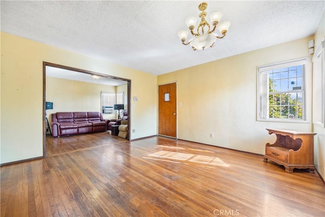 empty room with wood-type flooring, a textured ceiling, and an inviting chandelier