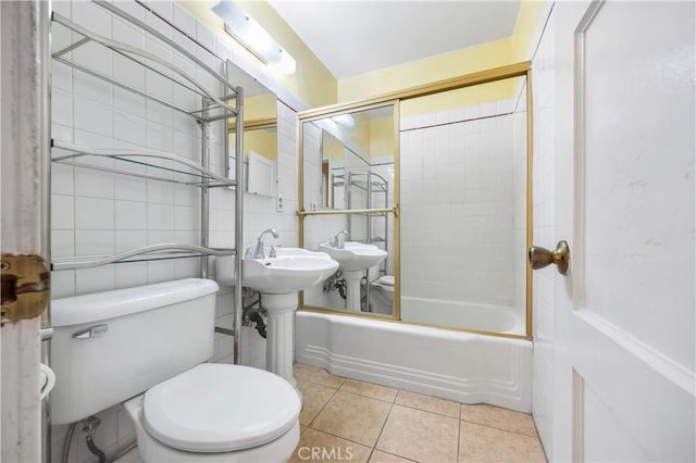 bathroom with toilet, tiled shower / bath, tile patterned floors, and tile walls