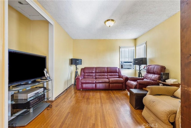 living room with hardwood / wood-style floors, cooling unit, and a textured ceiling