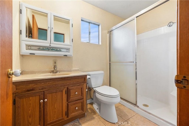 bathroom featuring tile patterned flooring, vanity, toilet, and a shower with shower door