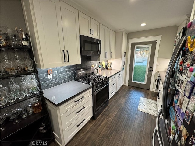 kitchen with dark hardwood / wood-style floors, decorative backsplash, white cabinetry, and appliances with stainless steel finishes