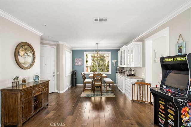 dining area with crown molding, dark wood-type flooring, and a notable chandelier