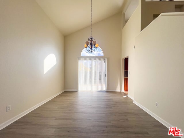 unfurnished dining area featuring a chandelier, dark hardwood / wood-style flooring, and high vaulted ceiling