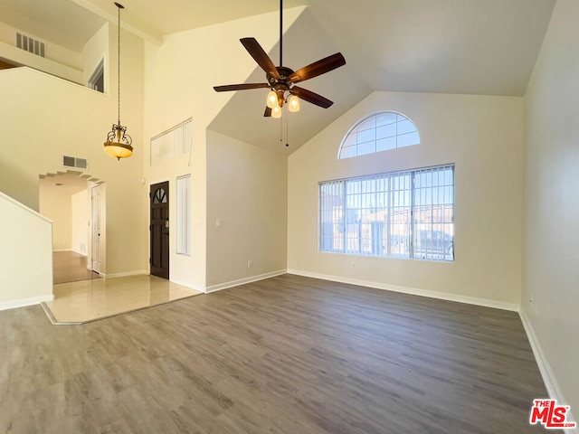 unfurnished living room with ceiling fan, wood-type flooring, and high vaulted ceiling