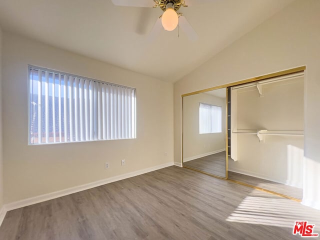 unfurnished bedroom featuring ceiling fan, vaulted ceiling, wood-type flooring, and a closet