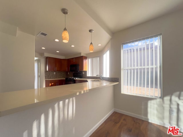 kitchen with decorative backsplash, sink, black appliances, dark hardwood / wood-style floors, and hanging light fixtures