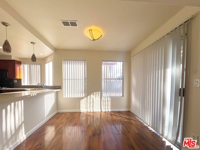 kitchen with decorative backsplash, sink, hanging light fixtures, and hardwood / wood-style flooring