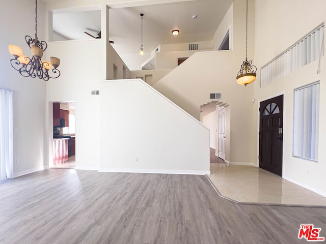 interior space with high vaulted ceiling, ceiling fan with notable chandelier, and hardwood / wood-style flooring