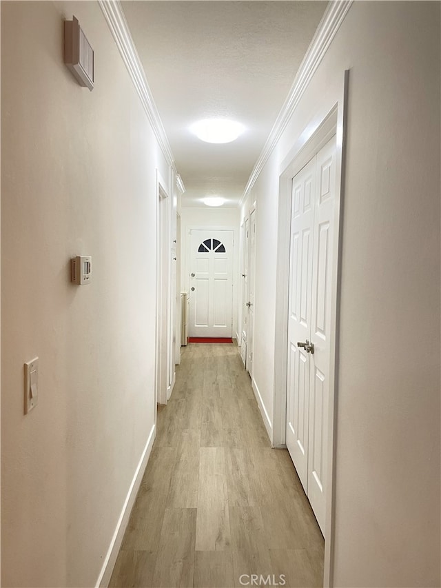 hall with light hardwood / wood-style flooring and crown molding