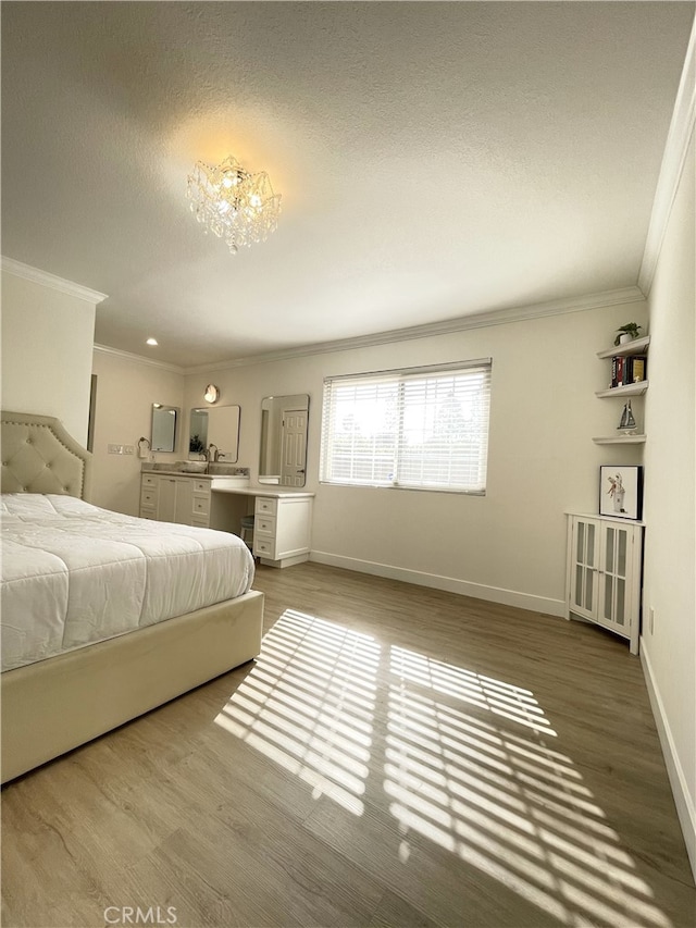 bedroom with sink, a notable chandelier, a textured ceiling, hardwood / wood-style flooring, and ornamental molding