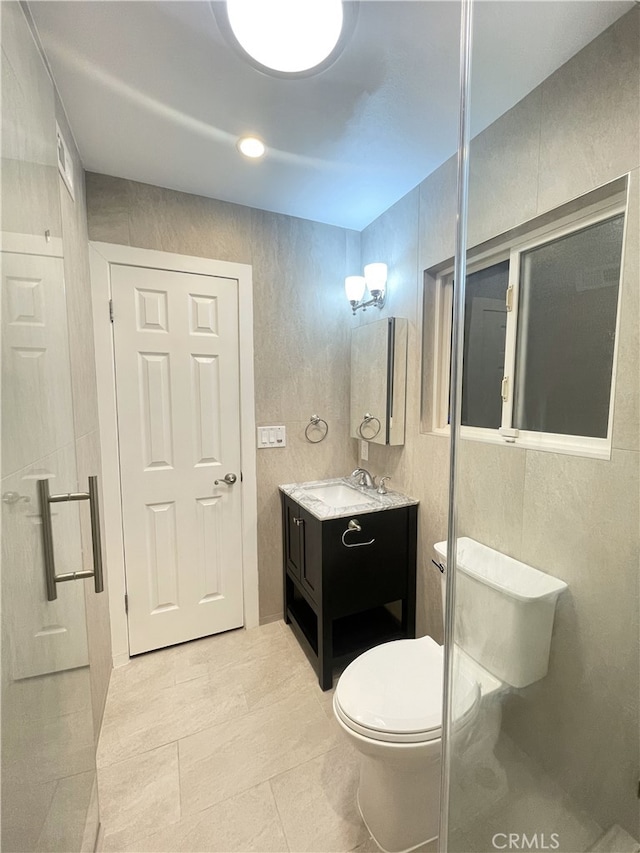 bathroom featuring tile patterned flooring, a chandelier, toilet, vanity, and tile walls