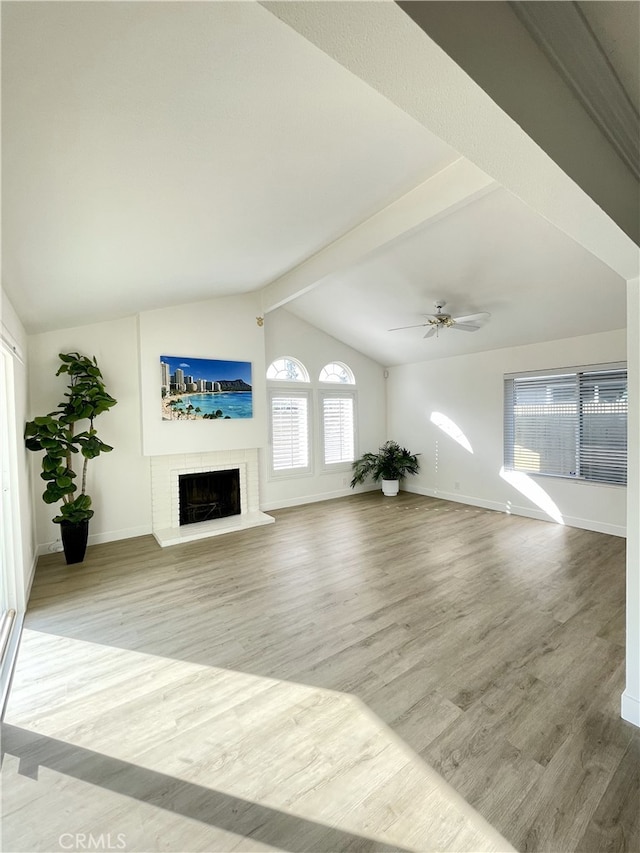 unfurnished living room featuring a fireplace, vaulted ceiling with beams, light hardwood / wood-style floors, and ceiling fan