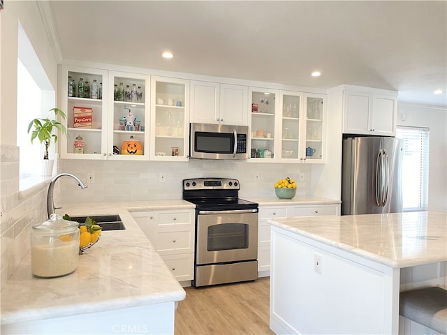 kitchen with stainless steel appliances, white cabinetry, tasteful backsplash, and sink