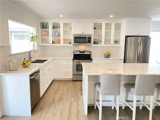 kitchen with white cabinets, sink, a kitchen bar, and stainless steel appliances