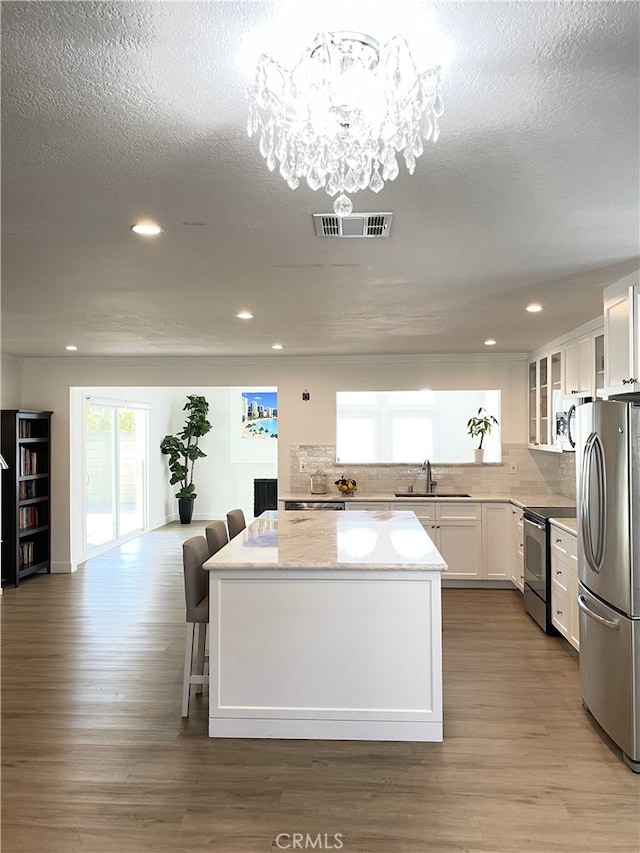 kitchen featuring an inviting chandelier, white cabinets, sink, light wood-type flooring, and appliances with stainless steel finishes