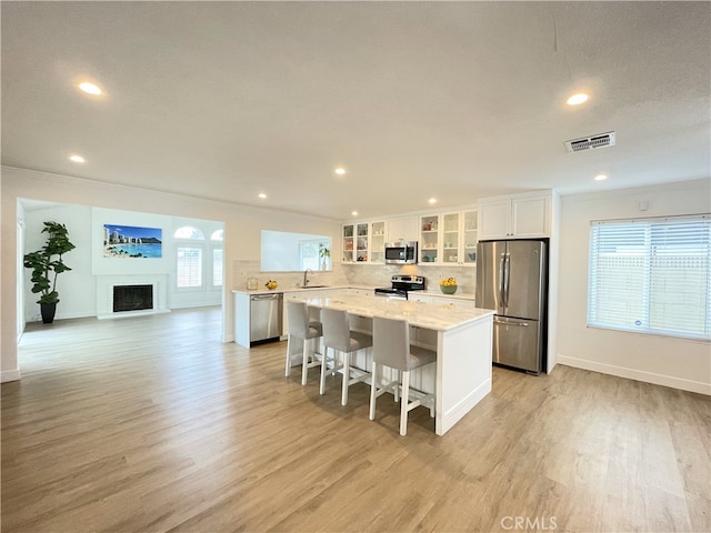 kitchen featuring a wealth of natural light, a kitchen island, white cabinets, and appliances with stainless steel finishes