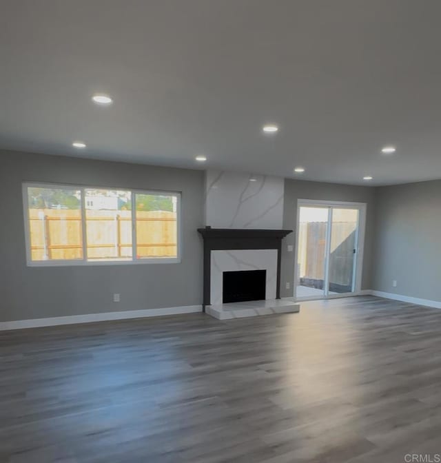 unfurnished living room with dark wood-type flooring and a high end fireplace