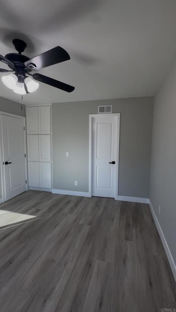 unfurnished bedroom featuring ceiling fan and dark hardwood / wood-style floors