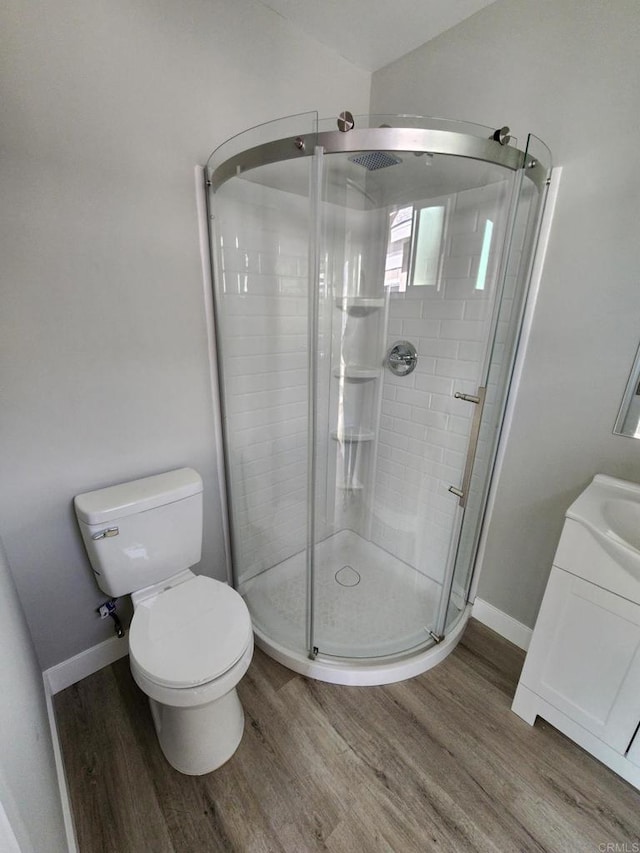 bathroom with hardwood / wood-style flooring, vanity, toilet, and walk in shower