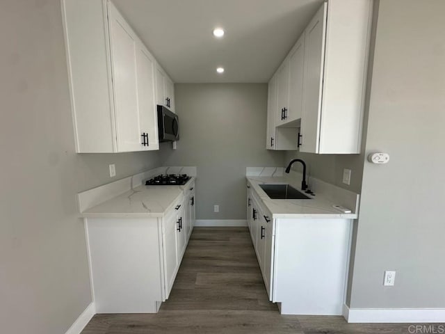 kitchen featuring light stone countertops, white cabinetry, sink, dark wood-type flooring, and black gas cooktop