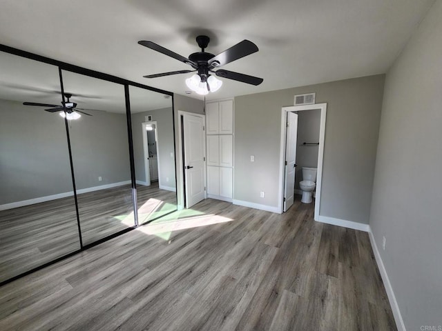 unfurnished bedroom with ceiling fan, ensuite bathroom, and light hardwood / wood-style floors