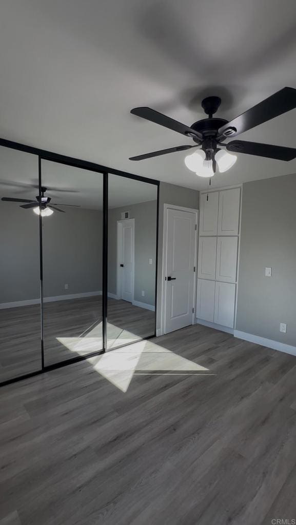 unfurnished bedroom with wood-type flooring, a closet, and ceiling fan