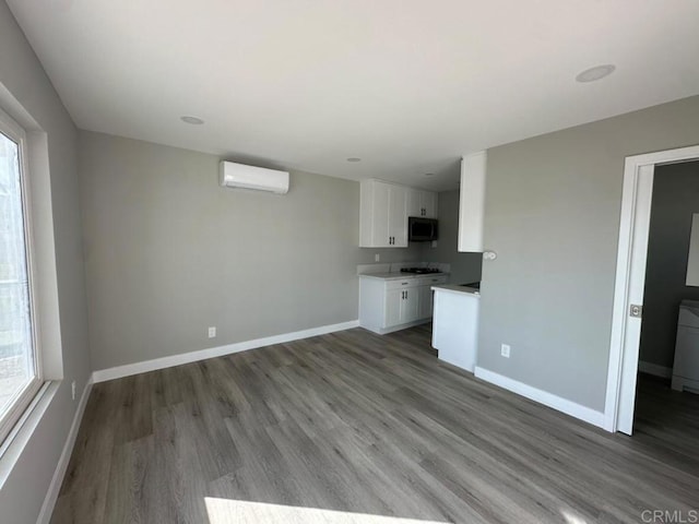 unfurnished living room with a wall unit AC and wood-type flooring