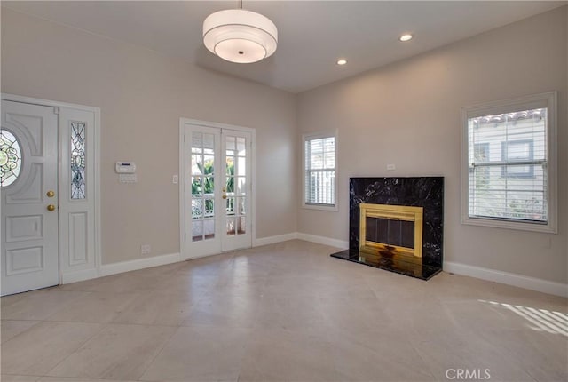 unfurnished living room with a high end fireplace and french doors