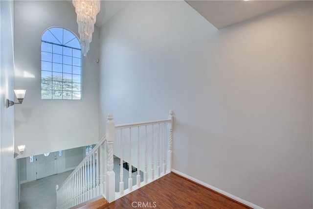 stairs with wood-type flooring and a notable chandelier