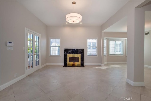 unfurnished living room featuring french doors, a high end fireplace, and light tile patterned floors