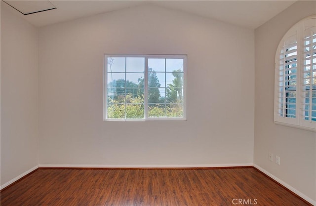 spare room featuring lofted ceiling and dark hardwood / wood-style floors