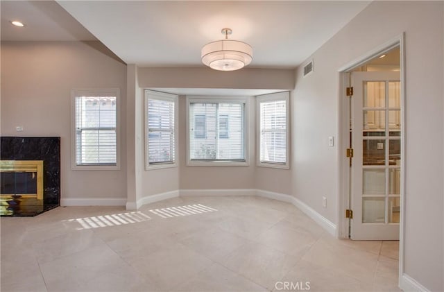 unfurnished dining area with a wealth of natural light, a fireplace, and light tile patterned floors