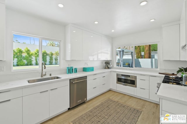 kitchen featuring white cabinets, stainless steel appliances, plenty of natural light, and sink