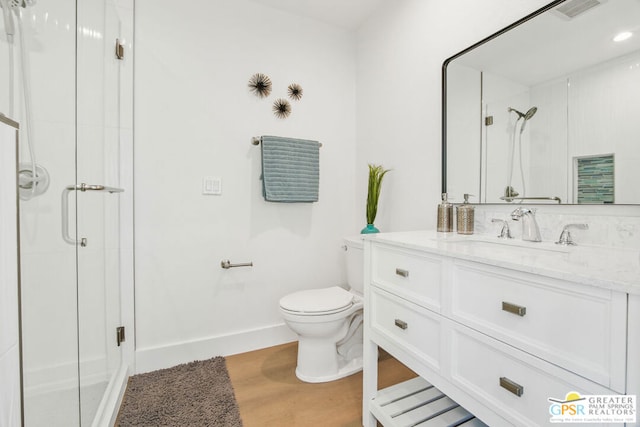 bathroom featuring vanity, wood-type flooring, a shower with shower door, and toilet