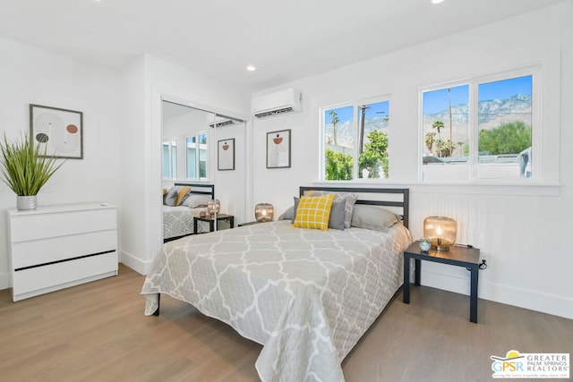 bedroom featuring a wall mounted air conditioner and light hardwood / wood-style flooring