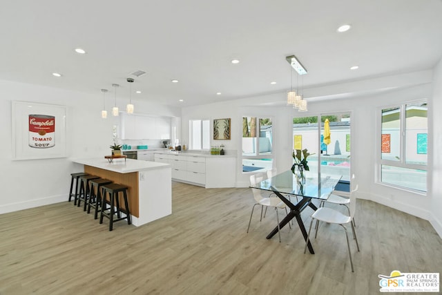 kitchen featuring kitchen peninsula, white cabinetry, pendant lighting, and light wood-type flooring