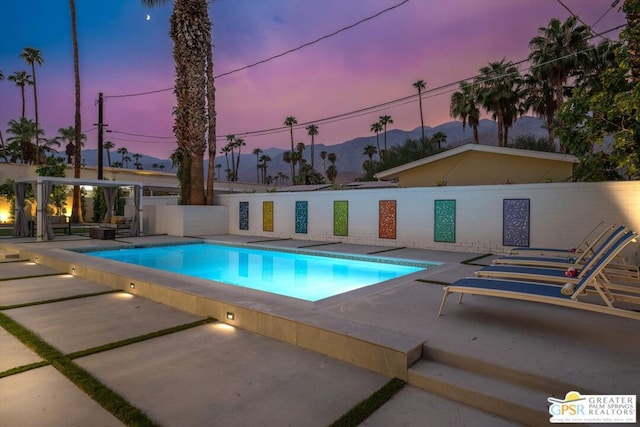 pool at dusk with a patio area