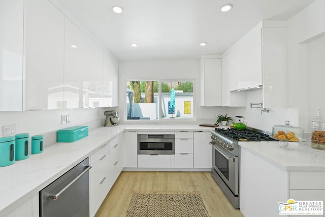 kitchen featuring white cabinetry, light stone countertops, light wood-type flooring, and appliances with stainless steel finishes