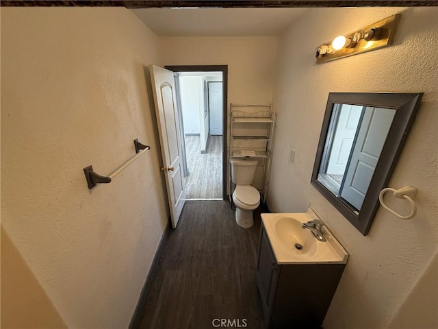 bathroom featuring wood-type flooring, vanity, and toilet