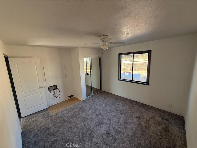 unfurnished bedroom with ceiling fan, a closet, dark carpet, and a textured ceiling