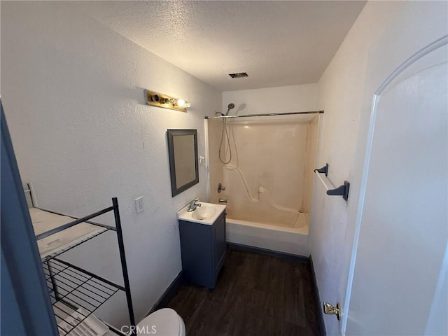 full bathroom with hardwood / wood-style floors, vanity, bathtub / shower combination, toilet, and a textured ceiling